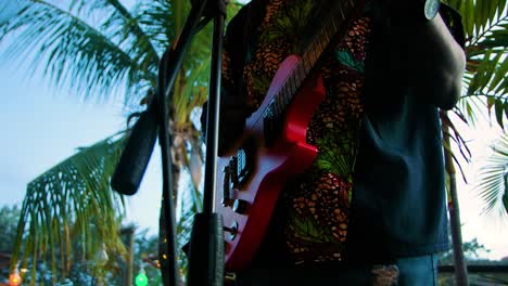 Reggae-guitar-artists-sings-and-grooves-to-the-tropical-beat,-closeup-of-hand-strumming-guitar