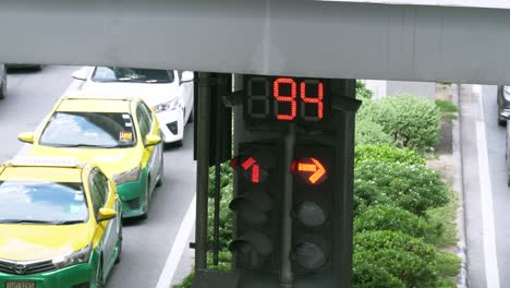 Taxis-and-other-vehicles-stopping-at-an-intersection-during-the-red-light-as-the-digital-traffic-counter-shows-when-will-be-the-green-light-for-the-traffic-to-go-in-Bangkok,-Thailand