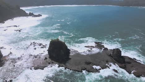 Bird's-eye-view-of-waves-crashing-on-a-coral-island-off-the-coast-of-Indonesia