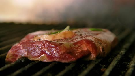 Grilling-beautiful-red-slab-of-steak-with-herbs-and-butter-on-top,-closeup-slow-motion-orbit