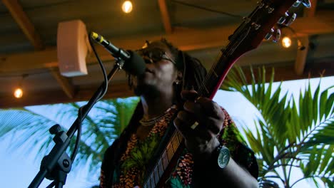 Slow-motion-pull-back-from-dark-reggae-artists-with-dreadlocks-vibing-as-they-sing-and-strum-guitar