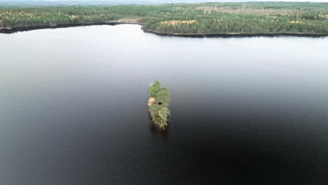 Lush-Islet-In-Middle-Of-Lake-With-Black-Waters-And-Fir-Forest-During-Autumn-In-Sweden