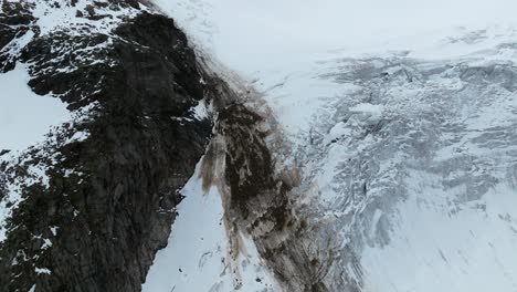 Aerial-view-capturing-stone-falls-on-a-glacier's-surface-in-the-Hohe-Tauern,-juxtaposing-rough-stone-against-smooth-icy-expanses