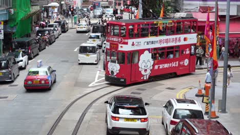 En-Las-Calles-De-Hong-Kong,-Un-Tranvía-Avanza-Hasta-La-Siguiente-Parada-Mientras-Los-Vehículos-Continúan