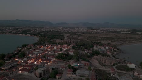 Establishing-aerial-view-over-Side-old-town-illuminated-neighbourhood-homes-at-sunset-with-Taurus-mountains-along-the-horizon