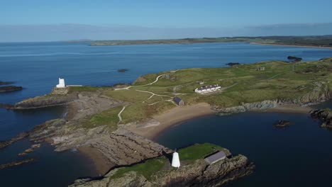 Aerial-view-circling-Ynys-Llanddwyn-island-lighthouse-and-beacon-surrounded-by-Irish-sea-at-sunrise