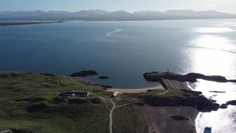 Aerial-view-across-Ynys-Llanddwyn-island-pilots-cottages-with-hazy-Snowdonia-mountain-range-across-shimmering-Irish-sea-at-sunrise