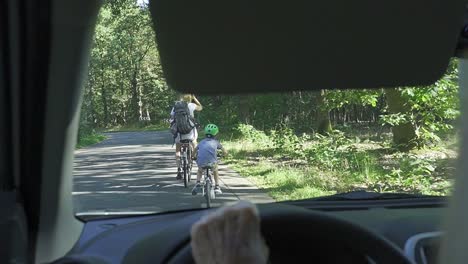 Grandmother-driving-car-with-bicycles-in-front-of-her-on-the-forest-road