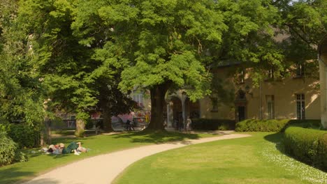 Pan-shot-of-locals-relaxing-in-the-garden-of-Abbey-de-la-Cambre-in-Brussels,-Belgium-on-a-sunny-day