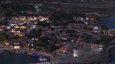 Aerial-view-flying-across-Side-old-town-marina-and-illuminated-Turkish-waterfront-neighbourhood