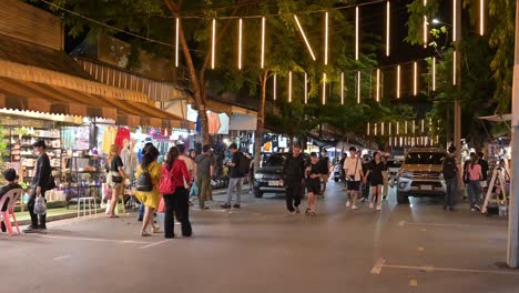 Gente-Subiendo-Y-Bajando-Por-La-Calle-Del-Mercado-Nocturno-Buscando-Algo-Para-Comprar-Y-Comer-En-Chatuchak,-Bangkok,-Tailandia