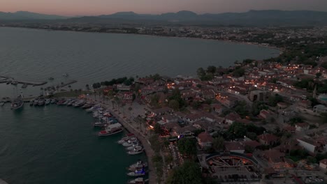 Aerial-view-circling-illuminated-Side-old-town-waterfront-neighbourhood-and-Mediterranean-marina-at-sunset
