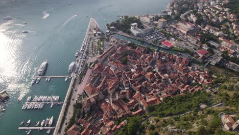 Kotor-Montenegro:-Coastal-aerial-tilt-up-reveal-showcasing-old-town-and-mountains