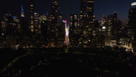 Aerial-pull-back-over-the-Central-park-away-from-the-7th-avenue,-night-in-Manhattan,-NY