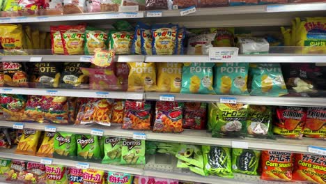 Variety-of-Japanese-Potato-chips-in-Colorful-packaging-display-at-Japanese-market-shelfs,-pan-shot