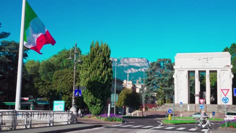 Part-of-the-Talfer-Bridge-with-Victory-Monument-and-Italian-flag-on-a-sunny-day-in-Bozen,-South-Tyrol