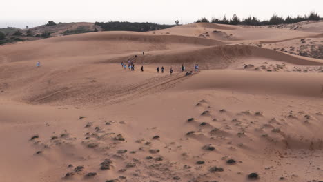 Tourist-Strolling-And-Enjoying-Sand-Sledding-On-Red-Sand-Dunes-Of-Mui-Ne-At-Sunset-In-Vietnam