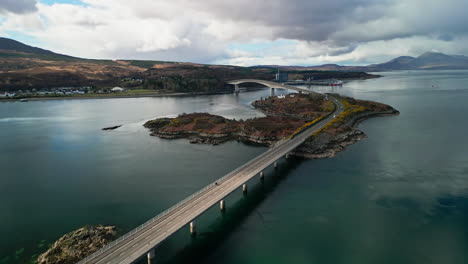 Wide-angle-overview-of-Skye-Bridge-scotland,-calm-waters-reflect-cloudy-sky-above