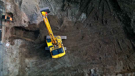 Static-aerial-top-down-view-of-excavator-rotating-on-tracks-in-construction-site