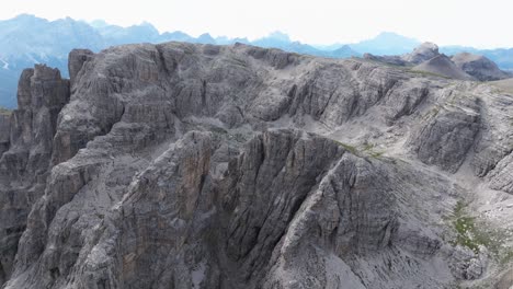 Aerial-view-of-Dolomites'-rugged-limestone-peaks,-deep-gorges,-and-scattered-vegetation
