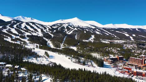 Snow-Covered-Winter-Mountain-Peaks-Aerial-Drone-View-with-Ski-Trails-Ready-for-Outdoor-Sports-and-Adventure-in-Beautiful-Thick-Pine-Tree-Forest