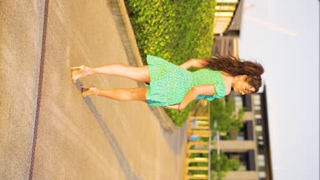 perfect-brunette-model-in-her-20s-walking-through-modern-park-with-a-wide-footpath-wearing-heels-and-cute-short-dress-posing-looking-over-her-shoulder-into-your-eyes-with-interest-slow-motion-vertical