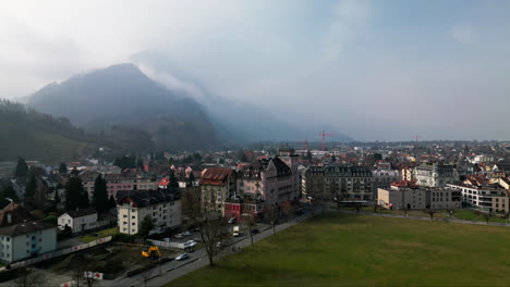 Panorámica-Aérea-Que-Establece-Una-Vista-De-Interlaken,-Suiza,-Mientras-Las-Nubes-Brumosas-Bajan-Por-La-Montaña