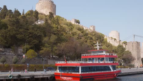 Crucero-Turístico-Rojo-Amarrado-A-Orillas-Del-Bósforo,-Fortaleza-De-Rumeli