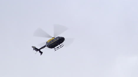 Während-Sich-Ein-Polizeihubschrauber-In-Einem-Bewölkten-Himmel-Hin-Und-Her-Bewegt,-Sieht-Man-Die-Besatzung-Aus-Dem-Fenster-Schauen