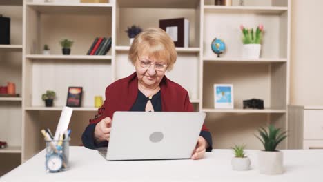 Una-Anciana-Abre-Alegremente-Su-Computadora-Portátil-Y-Comienza-A-Trabajar-Escribiendo-Texto