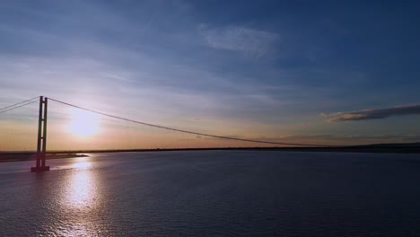 A-drone's-view:-Humber-Bridge-at-sunset,-cars-moving-gracefully-in-harmony
