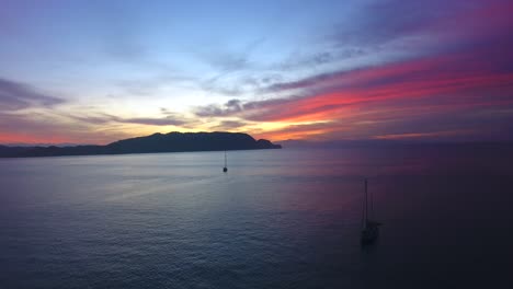 Unglaublicher,-Lebendiger-Sonnenuntergang-In-Der-Bucht-Von-Ballena,-Costa-Rica,-Der-über-Zwei-Verankerte-Segelboote-In-Einer-Ruhigen-Meeresbucht-Fliegt