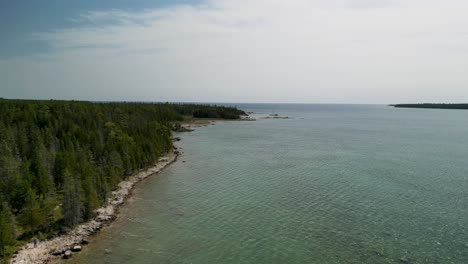 Aerial-ascent-up-forested-coastline,-Lake-Huron,-Michigan