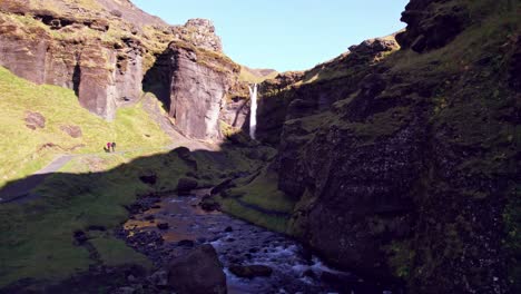 Aerial:-Right-to-left-reveal-of-Kvernufoss-horsetail-waterfall-is-in-a-hidden-alcove-where-you-can-go-behind-the-waterfall