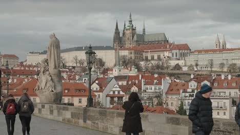 Tourists-at-Charles-Bridge-Prague,-and-Prague-Castle-in-the-background