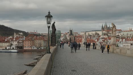 Tourists-on-Charles-Bridge,-Prague,-overlooking-the-city-and-Prague-Castle