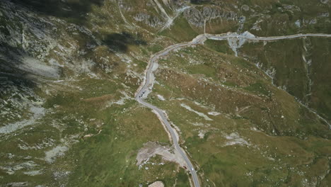 Top-down-perspective-of-Transalpina-in-Romania,-showcasing-the-meandering-road-amidst-verdant-rugged-landscapes-dotted-with-rock-formations