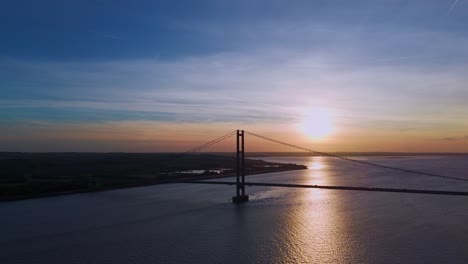 The-art-of-movement:-Aerial-view-of-Humber-Bridge-at-sunset,-cars-creating-a-visual-masterpiece