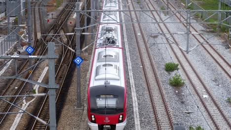 View-from-above-of-an-inter-provincial-train-leaving-the-train-station,-moving-at-the-center-forward-of-the-frame-in-Bangkok,-Thailand