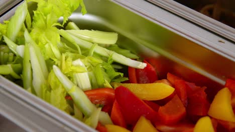Industrial-containers-brimming-with-freshly-chopped-veggies,-pepper-and-salad
