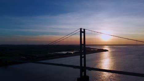 A-visual-symphony-unfolds-as-Humber-Bridge,-drenched-in-the-golden-hues-of-sunset,-frames-the-graceful-passage-of-cars