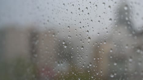 Raindrops-on-a-window-looking-out-to-gloomy,-overcast-weather