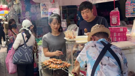 Vendors-sell-skewers-to-customers-in-the-famous-Yaowarat-Chinatown,-Bangkok,-Thailand