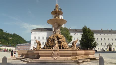 Brunnen-Mit-Fließendem-Wasser-Vor-Dem-Salzburger-Dom-Mit-Herumlaufenden-Menschen