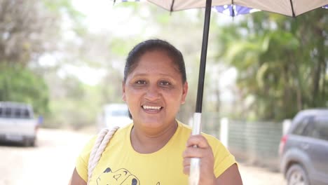 Portrait-of-an-adult-Latin-woman,-holding-an-umbrella-and-smiling-at-the-camera