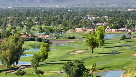 A-green-golf-course-in-Scottsdale,-Arizona-with-lakes-and-sprinklers