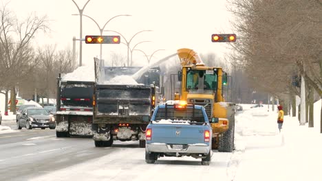 A-snow-plow-clears-the-road-and-sprays-the-snow-into-a-truck-driving-next-to-him