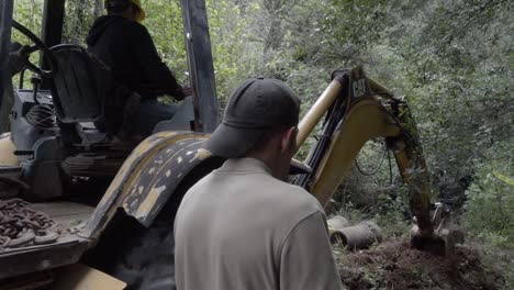 A-backhoe-loader-digging-in-the-forest-for-the-installation-of-concrete-pipes