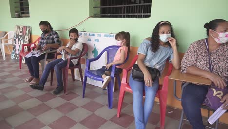 Women-and-children-sitting-waiting-for-a-medical-consultation-during-a-health-brigade,-in-an-improvised-clinic,-in-a-community-school-in-a-poor-area