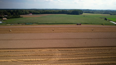 Luftaufnahme-Eines-Traktors,-Der-Auf-Einem-Weizenfeld-Auf-Dem-Land-In-Polen-Erntet